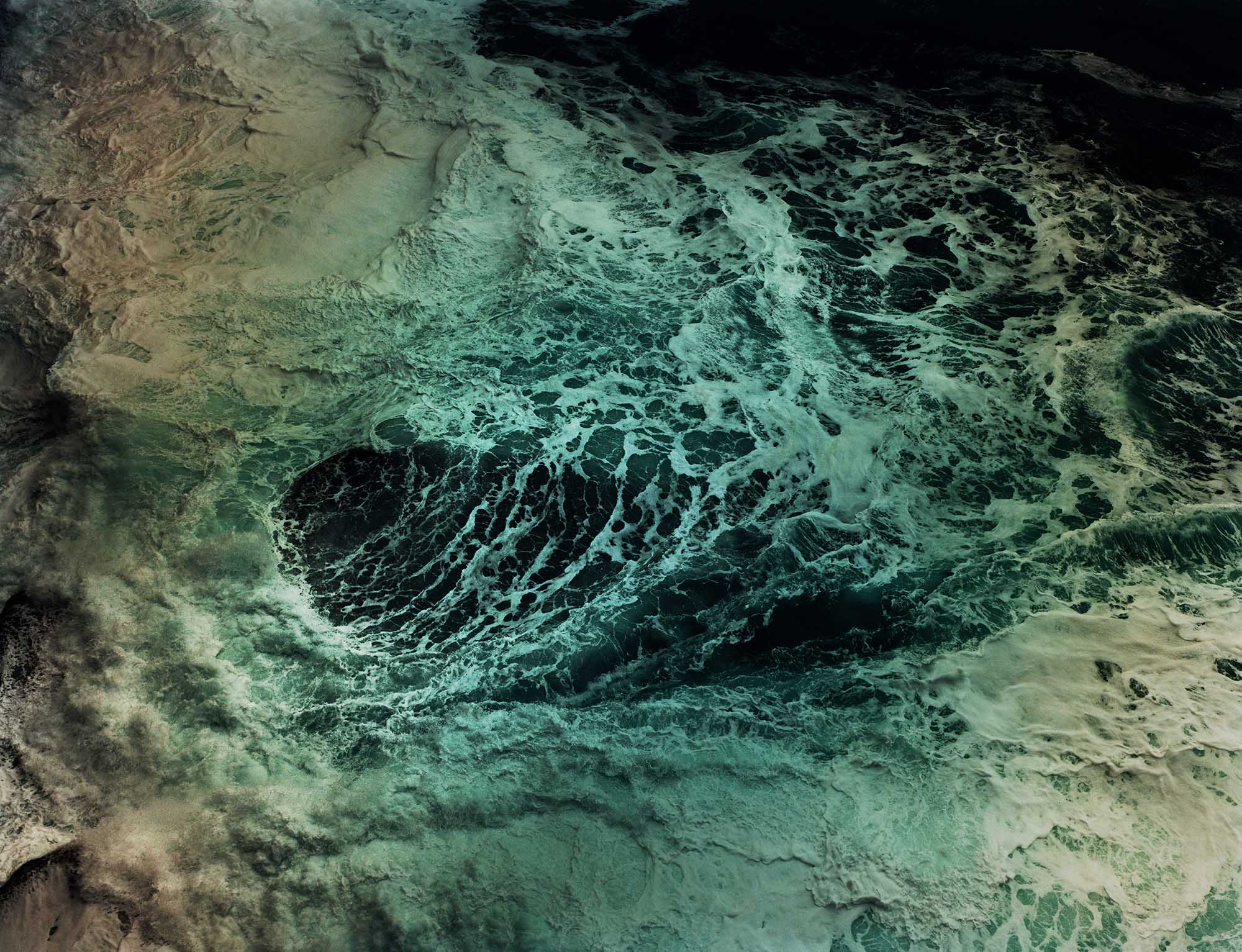 http://Abstract%20aerial%20view%20of%20turbulent%20ocean%20water%20with%20swirling%20teal%20and%20green%20currents,%20whitecaps,%20and%20a%20darker%20central%20depression.