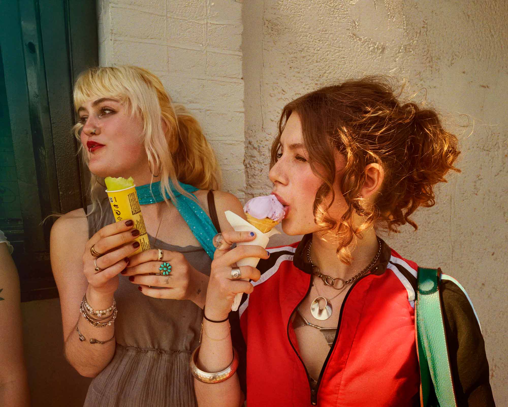 Here, the camera finds a moment of unspoken connection, steeped in the magic of golden hour light. The image explores the beautiful nuances of friendship—one friend lost in the simple pleasure of a lavender ice cream cone, her hair a halo of backlit curls, while the other pauses, her expression reflective. The details tell their own story: the eclectic mix of silver and turquoise jewelry, the contrast in their personal styles, the soft focus on their comfortable closeness. This photograph is a testament to the project's core belief: that the most profound moments are often the most fleeting and quiet ones, rich with genuine emotion and illuminated by beautiful, natural light.