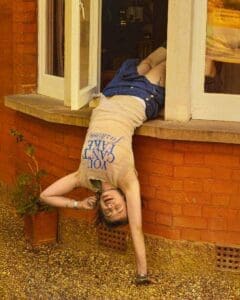 http://Young%20woman%20leaning%20out%20of%20living%20room%20window%20of%20victorian%20brick%20house%20in%20England.