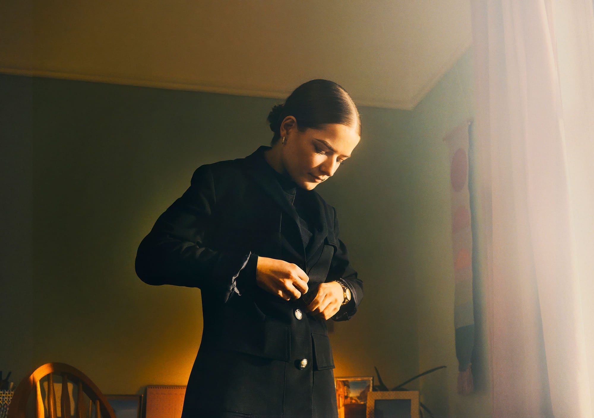 http://Woman%20putting%20on%20jacket%20in%20bedroom,%20green%20room,%20light,%20changing.%20A%20stills%20picture%20from%20photographer%20Ben%20Stockley's%20campaign%20for%20.Gov%20Department%20for%20Education%20(DfE)%20in%20England%20with%20M&C%20Saatchi.