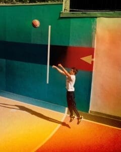 http://A%20young%20boy%20in%20a%20Levi's%20t-shirt%20jumping%20mid-air%20to%20shoot%20a%20basketball%20on%20a%20colorful%20outdoor%20court,%20with%20the%20ball%20in%20flight.