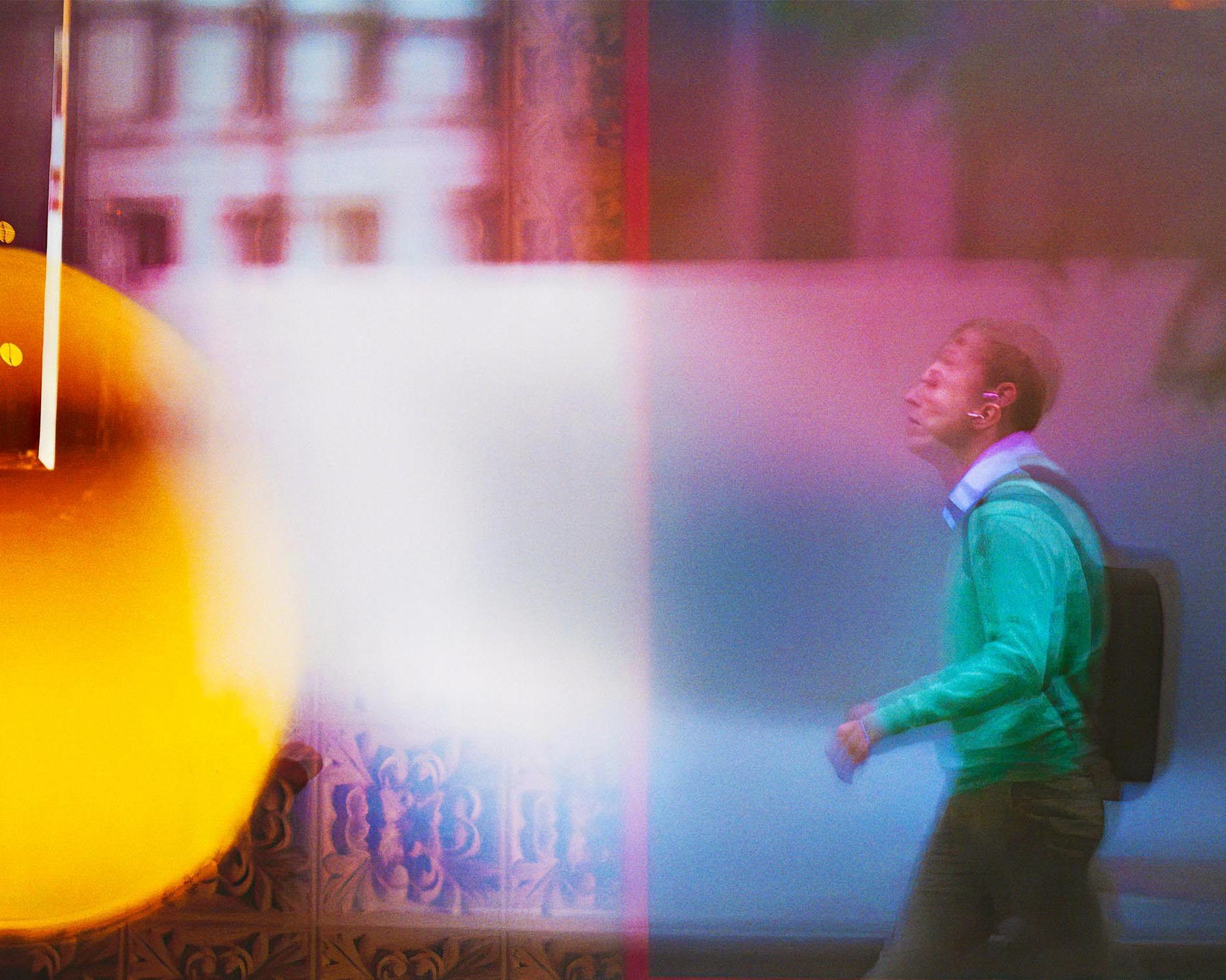 http://Motion-blurred%20image%20of%20a%20man%20in%20a%20green%20sweater%20walking,%20with%20strong%20color%20shifts%20and%20light%20flares%20creating%20an%20abstract%20effect